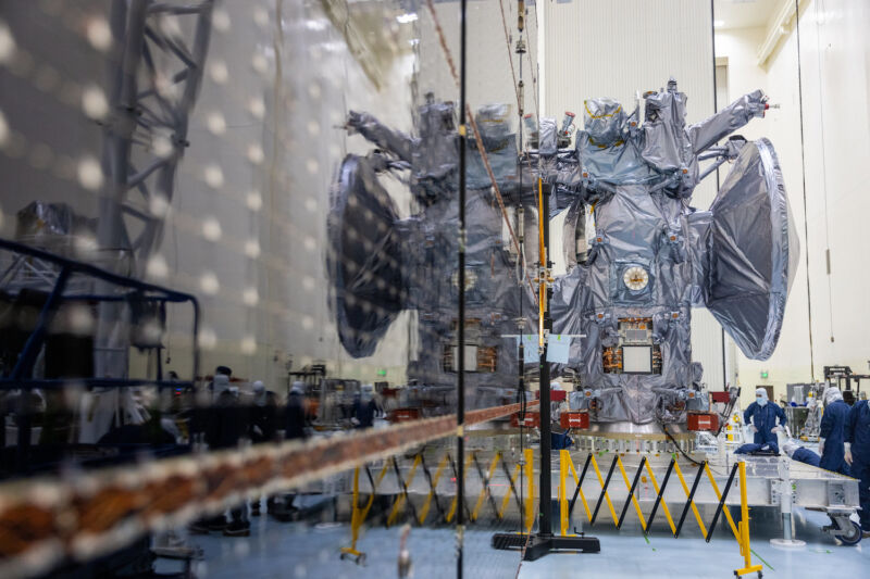 The main body of NASA's Europa Clipper spacecraft is reflected in one of the mission's deployable solar array wings during testing at Kennedy Space Center in Florida.