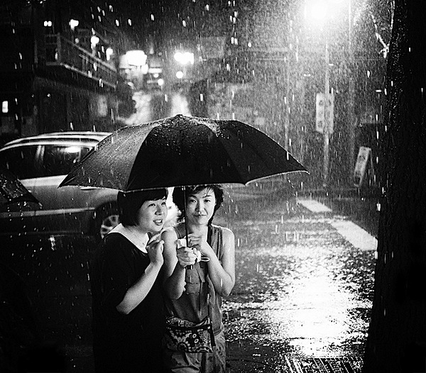 people huddled together in the rain street photography