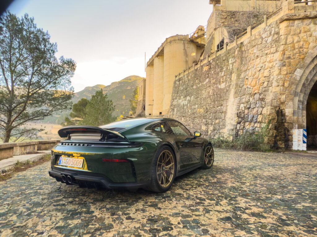 A green Porsche 911 GT3 parked next to what looks like it might be a castle.